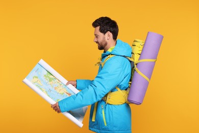 Photo of Man with backpack and map on orange background. Active tourism