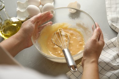 Woman with dough and ingredients for cake at light grey table, closeup