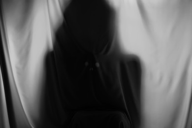 Silhouette of creepy ghost behind grey cloth