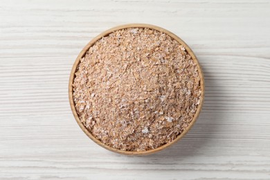 Photo of Bowl of wheat bran on white wooden table, top view
