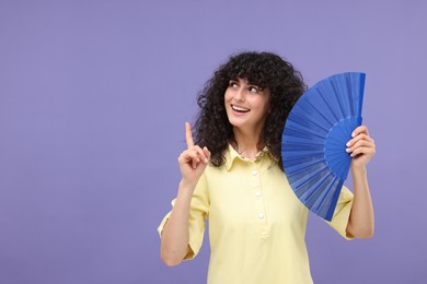 Photo of Happy woman holding hand fan on purple background. Space for text