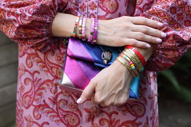 Photo of Woman with stylish purse wearing bracelets outdoors, closeup