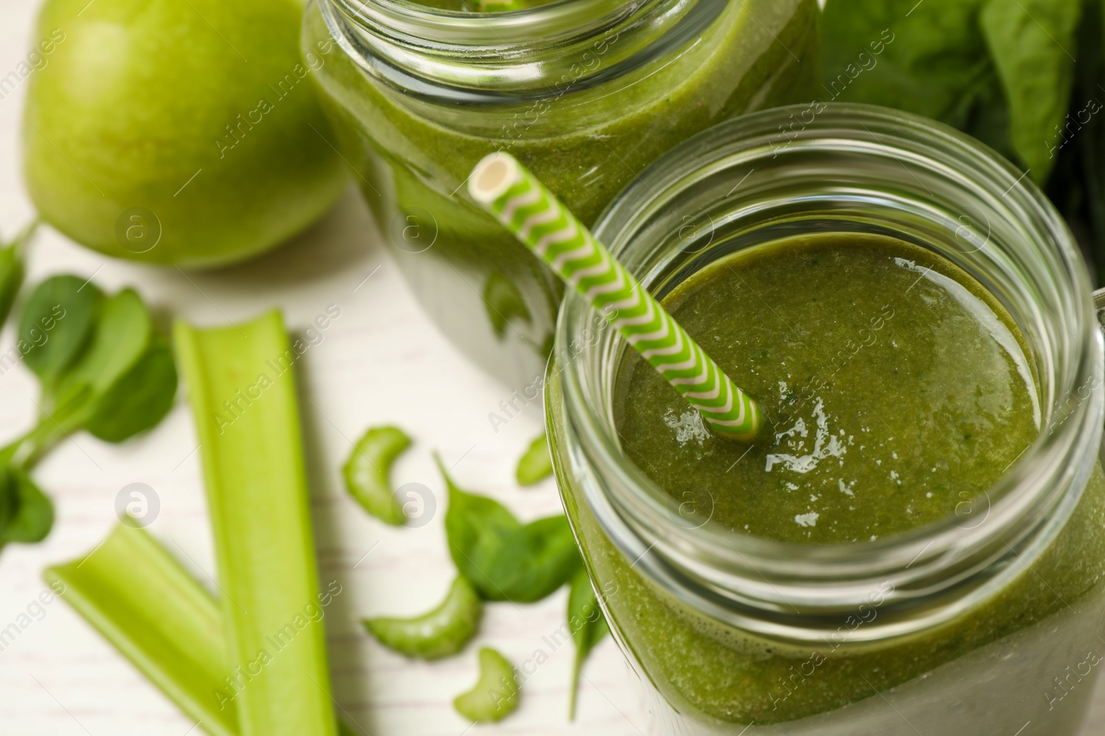 Photo of Delicious fresh green juice in mason jar on white table, closeup. Space for text