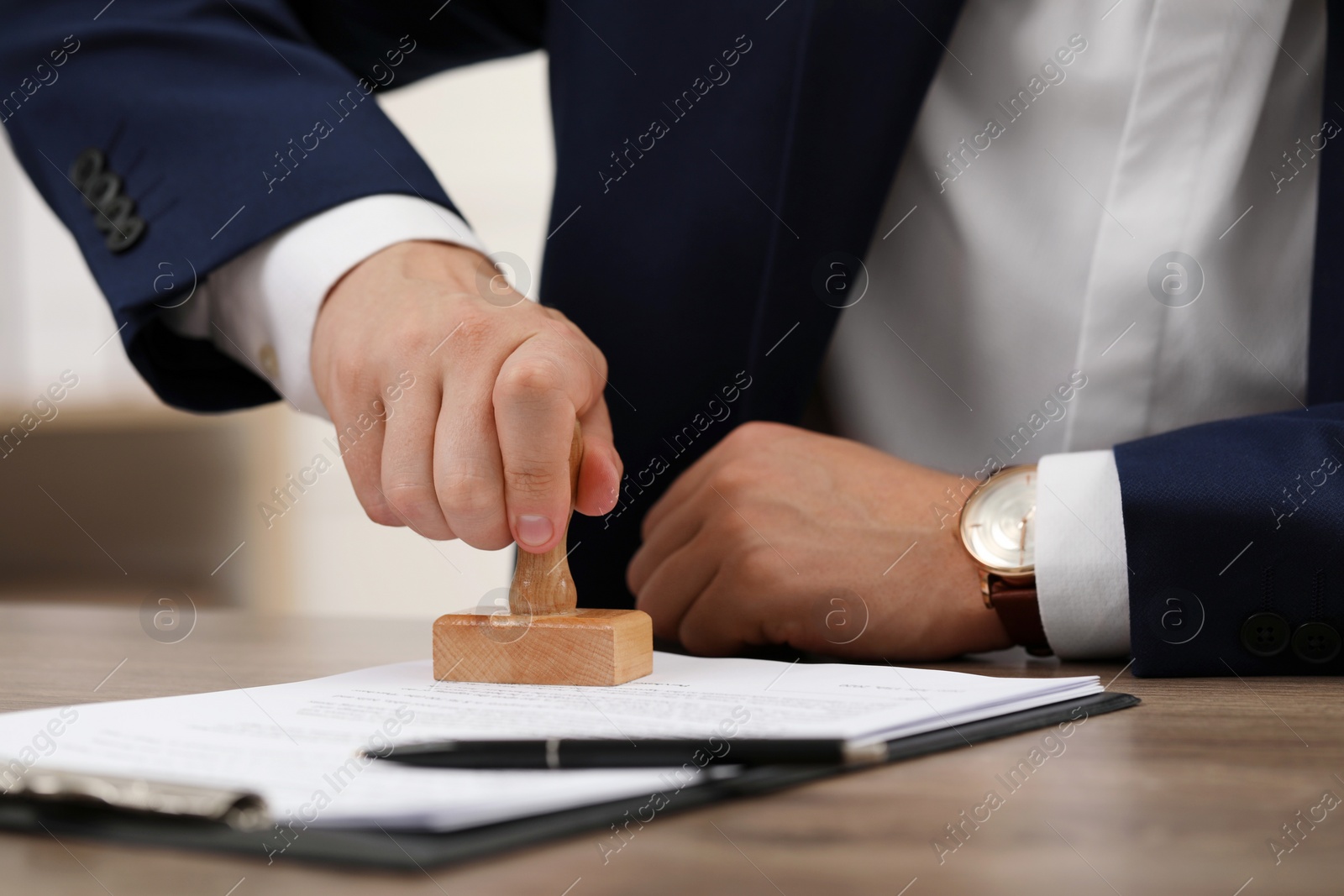 Photo of Man stamping document at table, closeup view