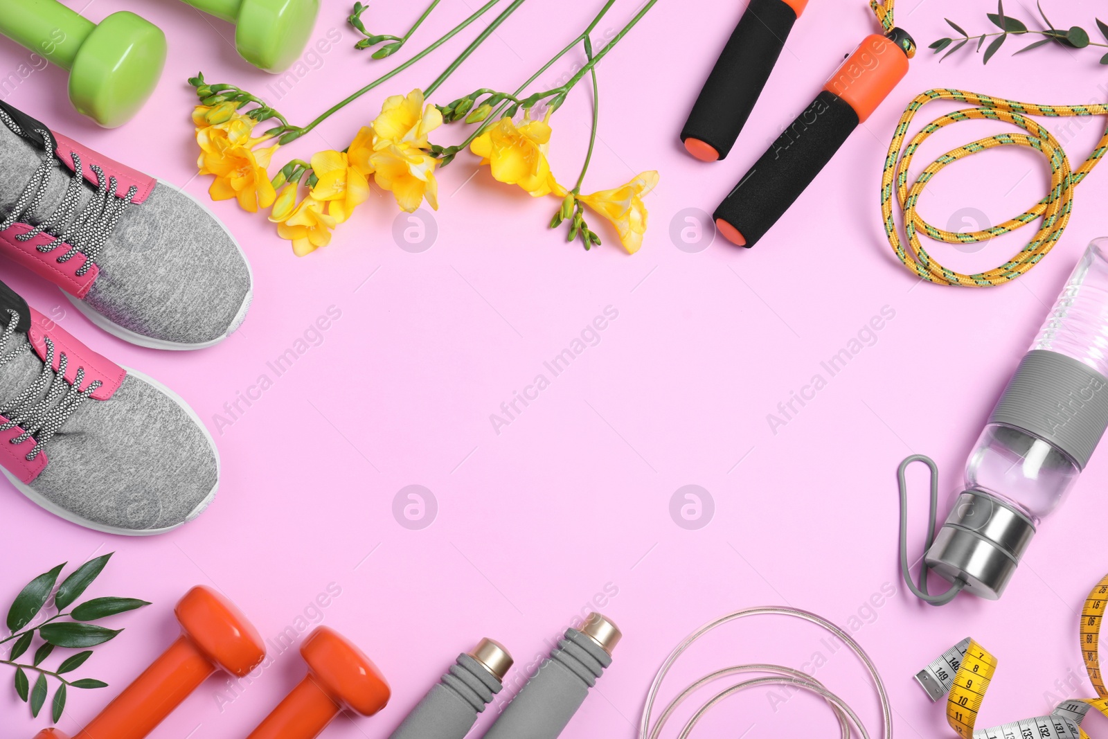 Photo of Frame made with spring flowers and sports items on pink background, flat lay. Space for text