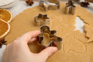 Photo of Woman cutting dough with cookie cutter at table, closeup. Christmas biscuits