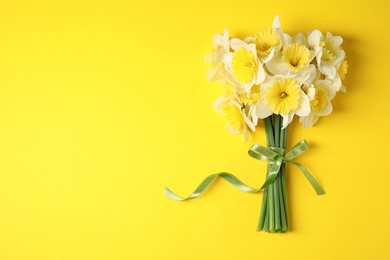 Photo of Bouquet of daffodils on color background, top view with space for text. Fresh spring flowers