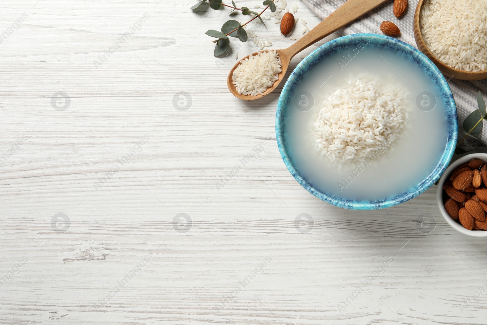 Photo of Flat lay composition with soaked rice on white wooden table. Space for text