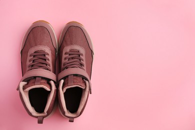 Photo of Pair of stylish kid's sneakers on pink background, top view. Space for text