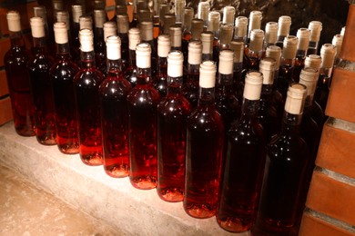 Photo of Many bottles of red wine on shelf in cellar