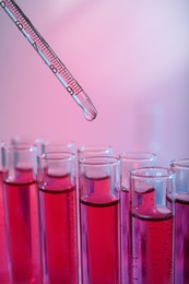 Photo of Dripping reagent into test tube with red liquid, closeup. Laboratory analysis