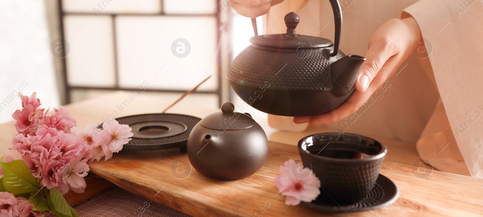 Image of Master conducting traditional tea ceremony at table indoors, closeup. Banner design