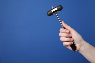 Photo of Woman holding reflex hammer on blue background, closeup with space for text. Nervous system diagnostic
