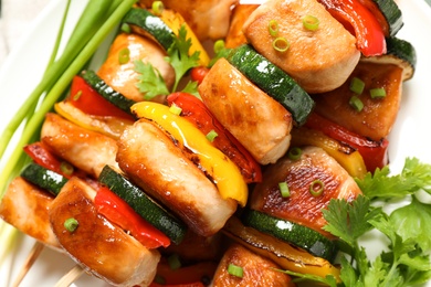 Photo of Delicious chicken shish kebabs with vegetables and parsley on plate, closeup