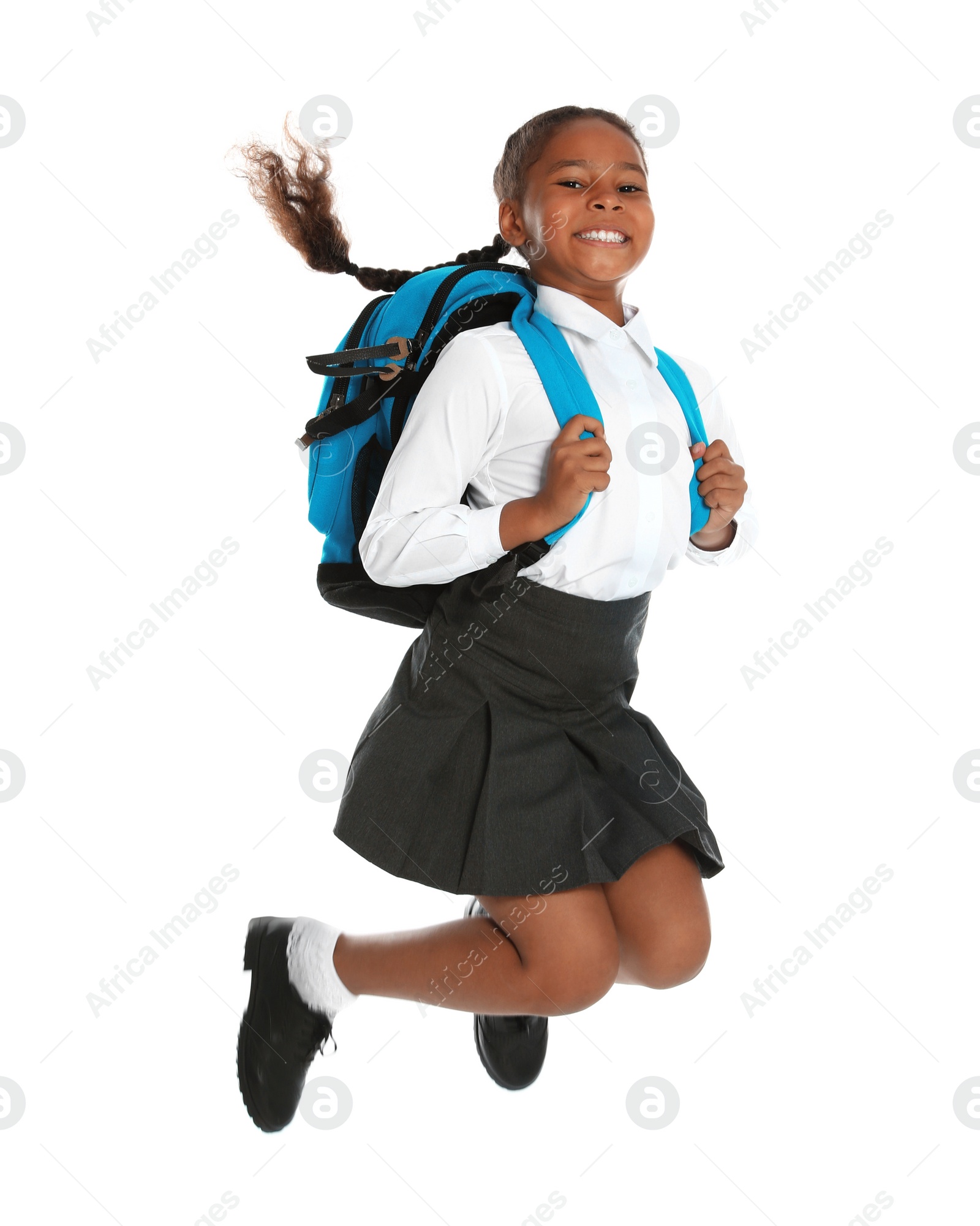 Photo of Happy African-American girl in school uniform jumping on white background