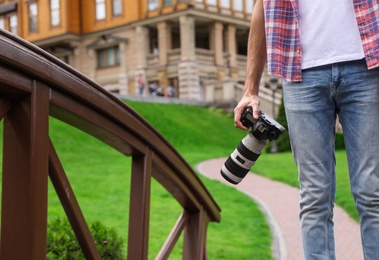 Photographer with professional camera in park, closeup