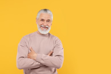 Photo of Portrait of handsome senior man on orange background. Space for text