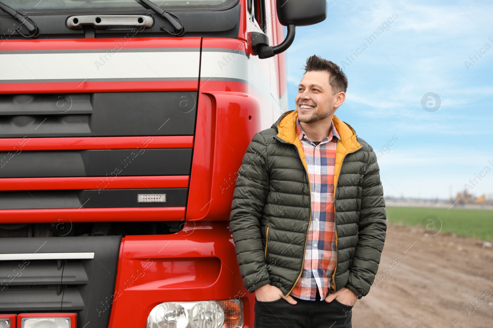 Photo of Portrait of happy driver at modern truck outdoors. Space for text