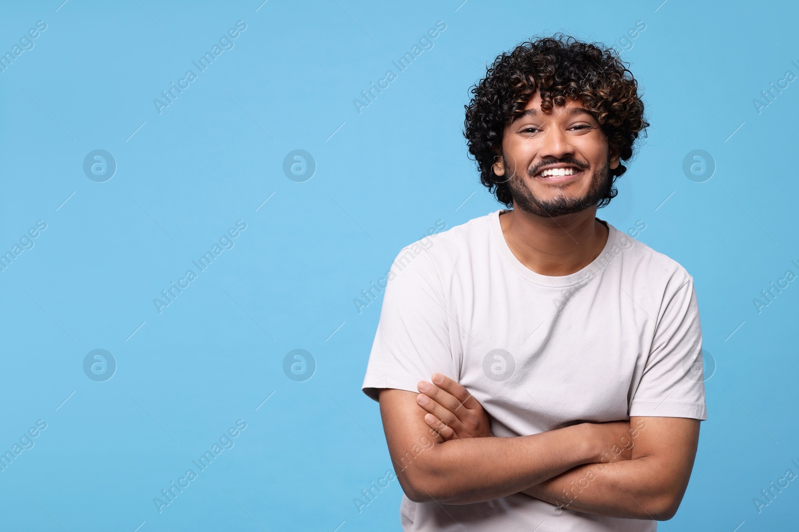 Photo of Handsome smiling man on light blue background, space for text