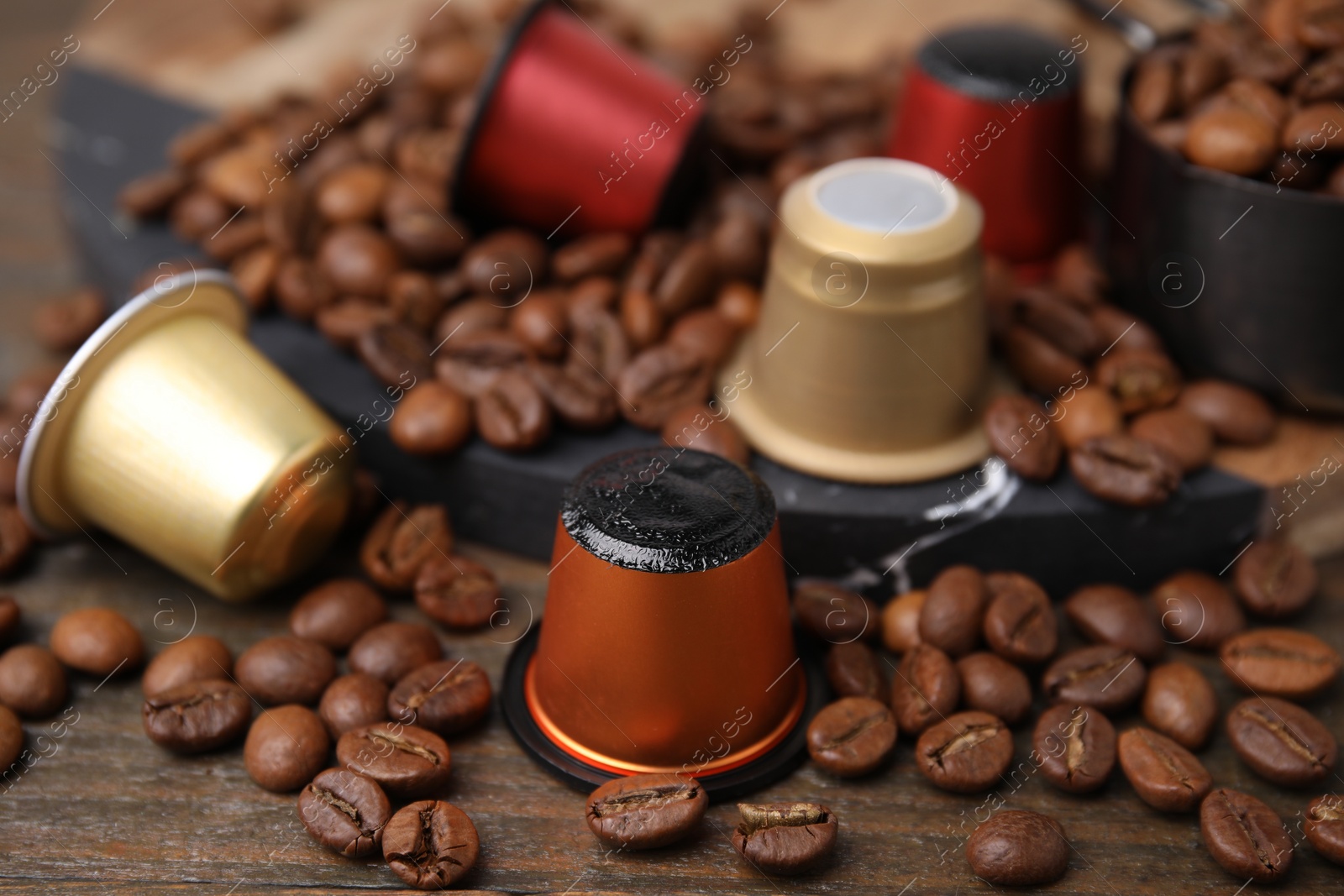Photo of Coffee capsules and beans on wooden table, closeup