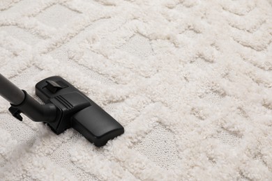 Hoovering carpet with modern vacuum cleaner. Space for text