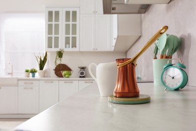 Photo of Cezve on white marble countertop in kitchen. Interior design