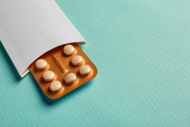 Photo of Birth control pills on light blue background. Space for text