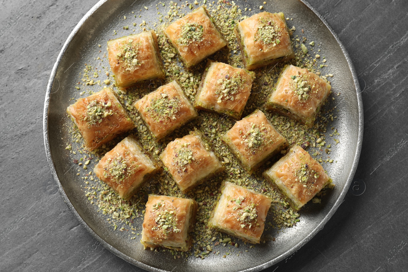 Photo of Delicious fresh baklava with chopped nuts on grey table, top view. Eastern sweets