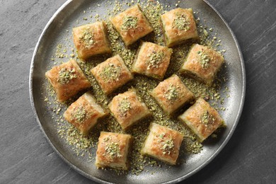 Photo of Delicious fresh baklava with chopped nuts on grey table, top view. Eastern sweets