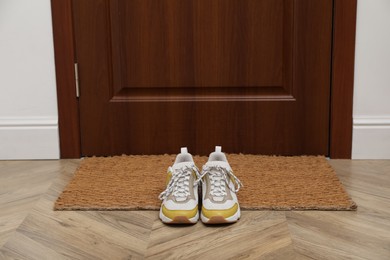 Photo of Stylish shoes near door mat in hall