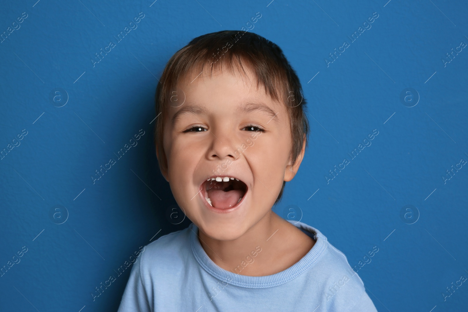 Photo of Portrait of excited little boy on blue background