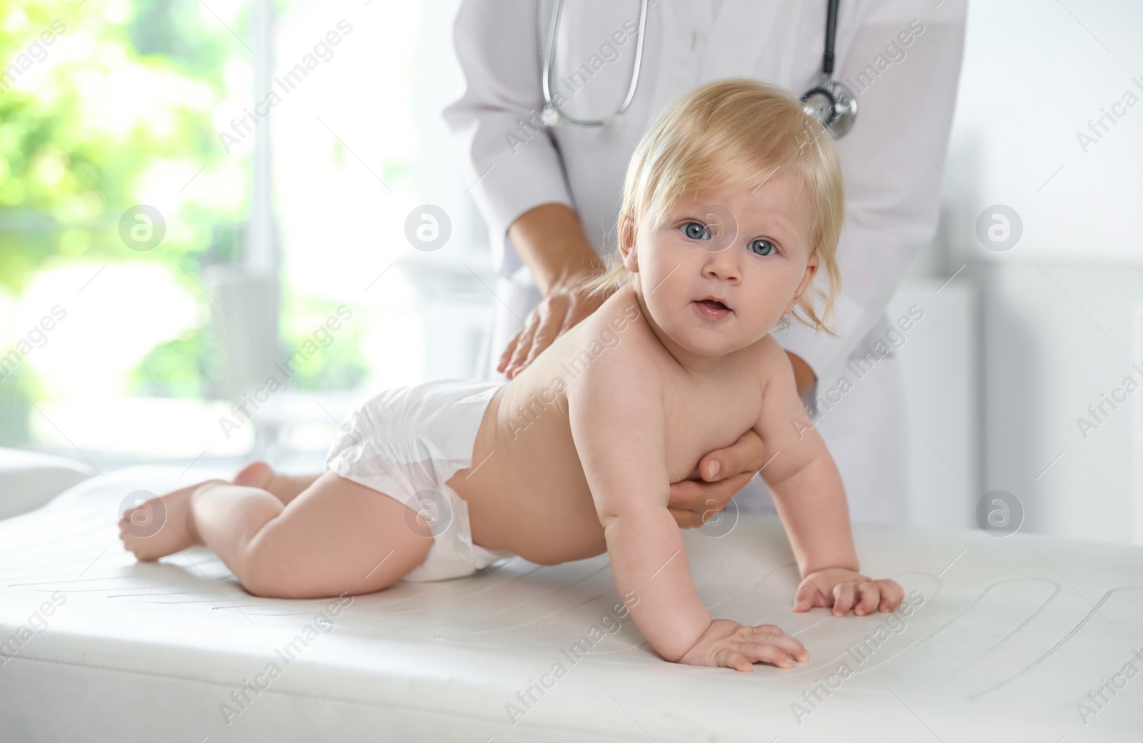 Photo of Pediatrician examining baby in hospital. Health care