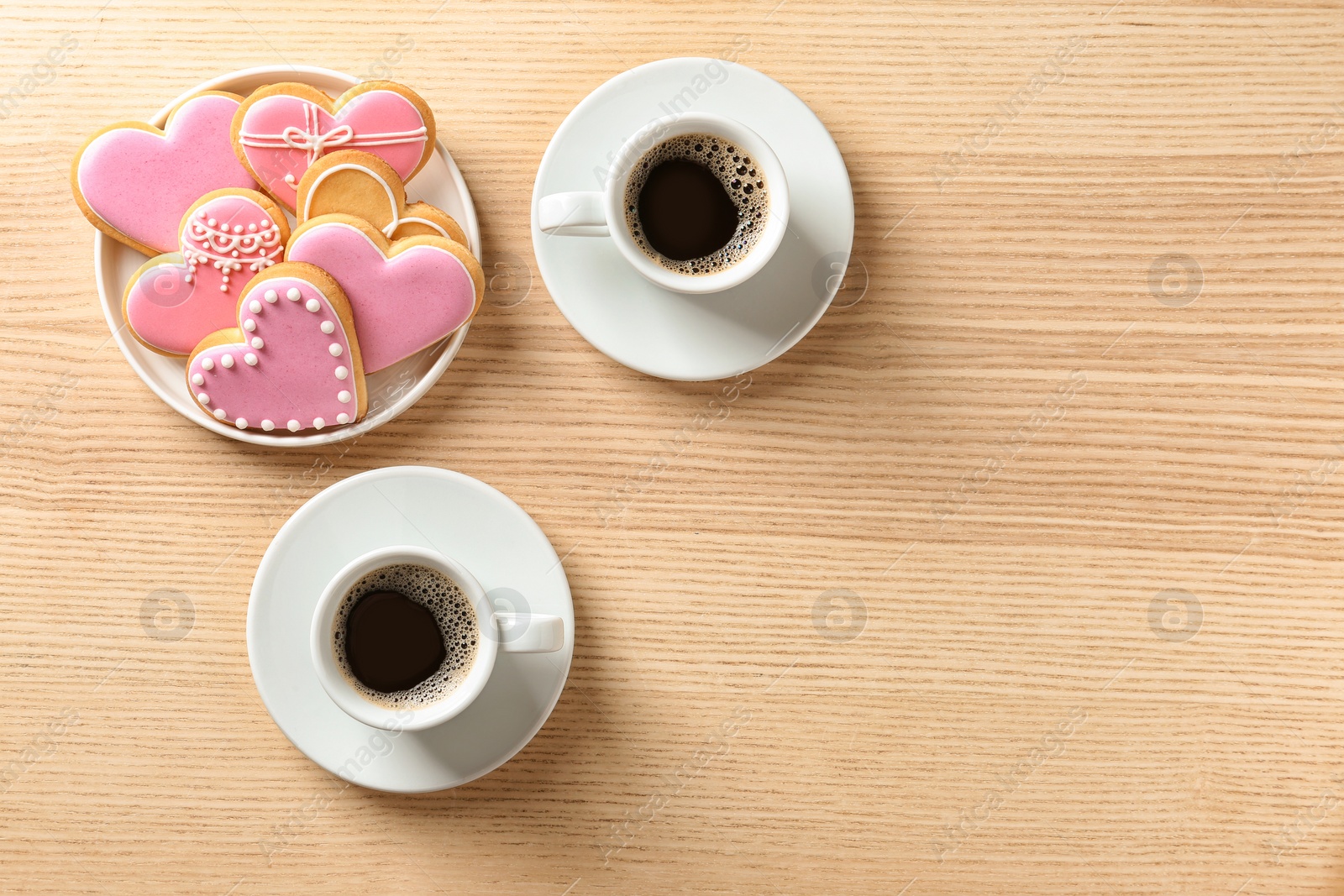 Photo of Romantic breakfast with heart shaped cookies and cups of coffee on wooden table, top view. Space for text