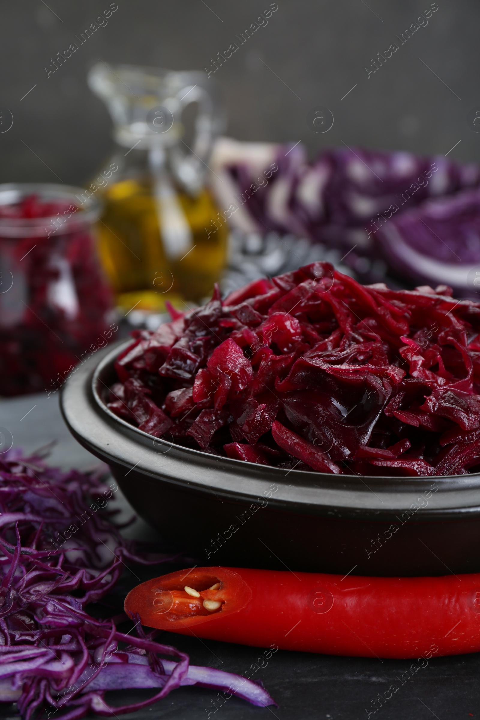 Photo of Tasty red cabbage sauerkraut and ingredients on grey table, closeup