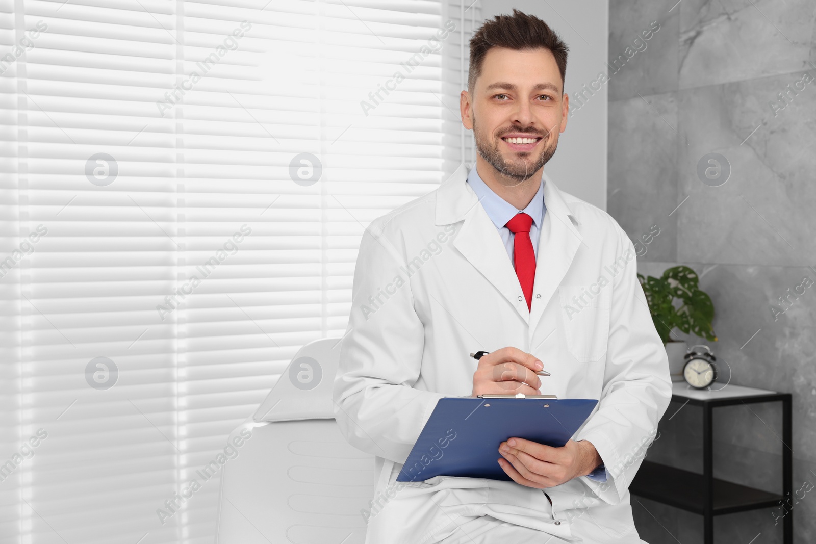 Photo of Happy doctor with clipboard in clinic, space for text. Patient consultation