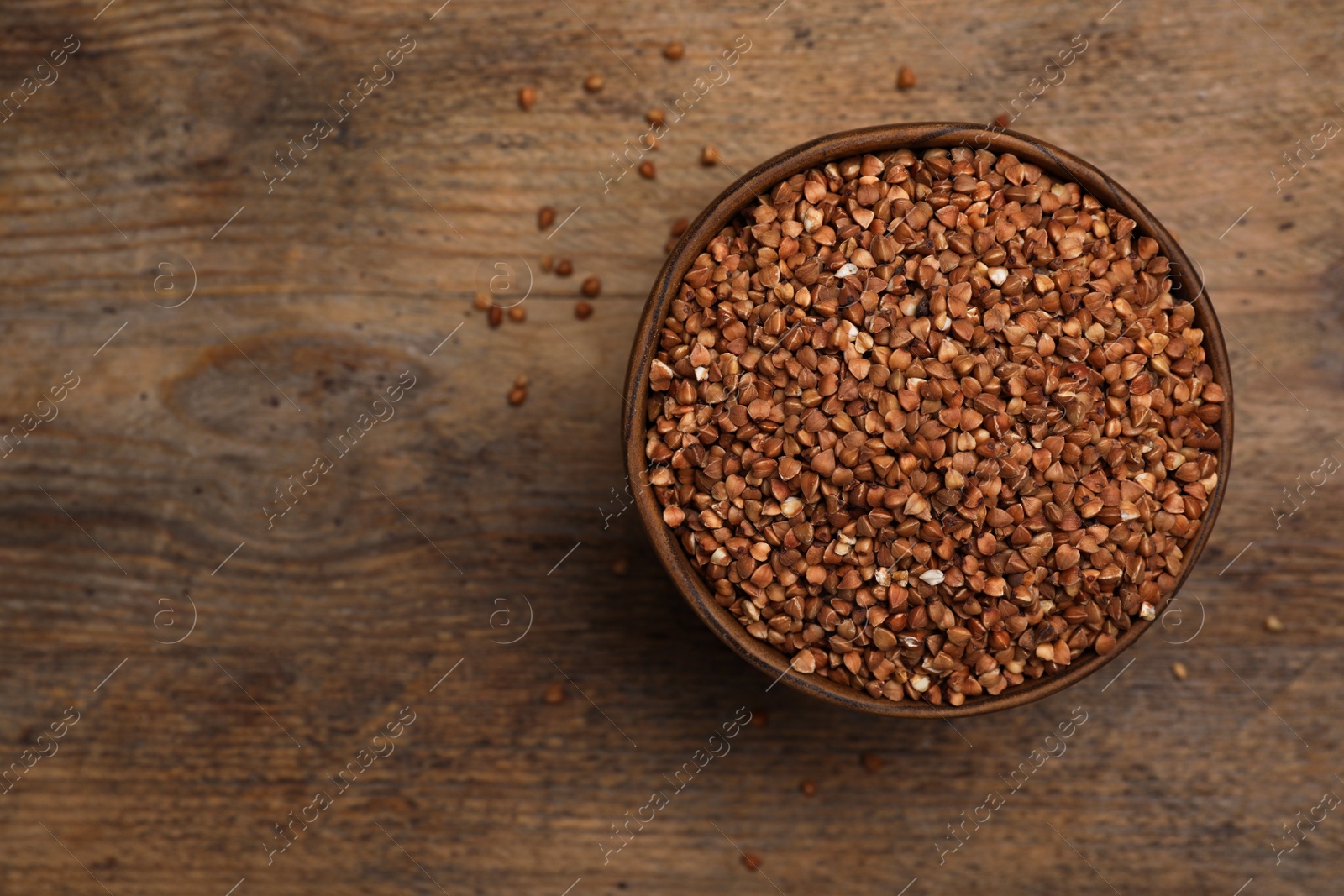 Photo of Buckwheat grains on wooden table, top view. Space for text