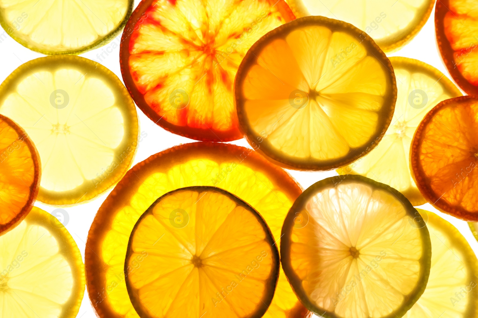 Photo of Illuminated slices of citrus fruits on white background, top view