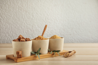 Bowls with different types of brown sugar on wooden table