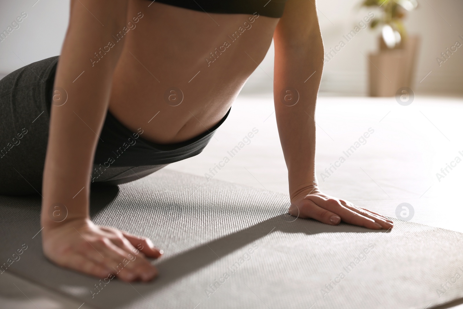 Photo of Young woman practicing cobra asana in yoga studio, closeup. Bhujangasana pose