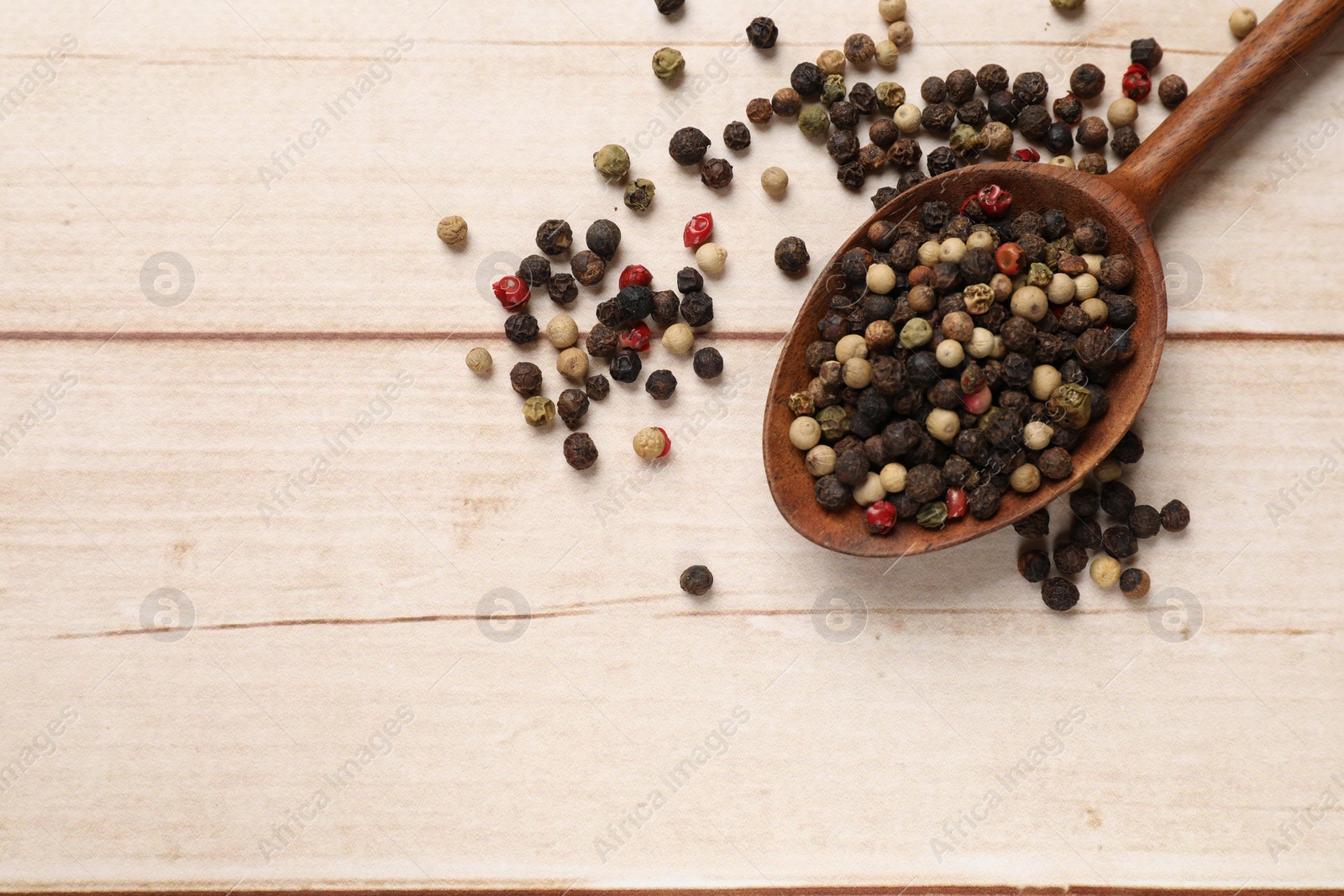 Photo of Aromatic spices. Different peppers in spoon on wooden table, top view and space for text