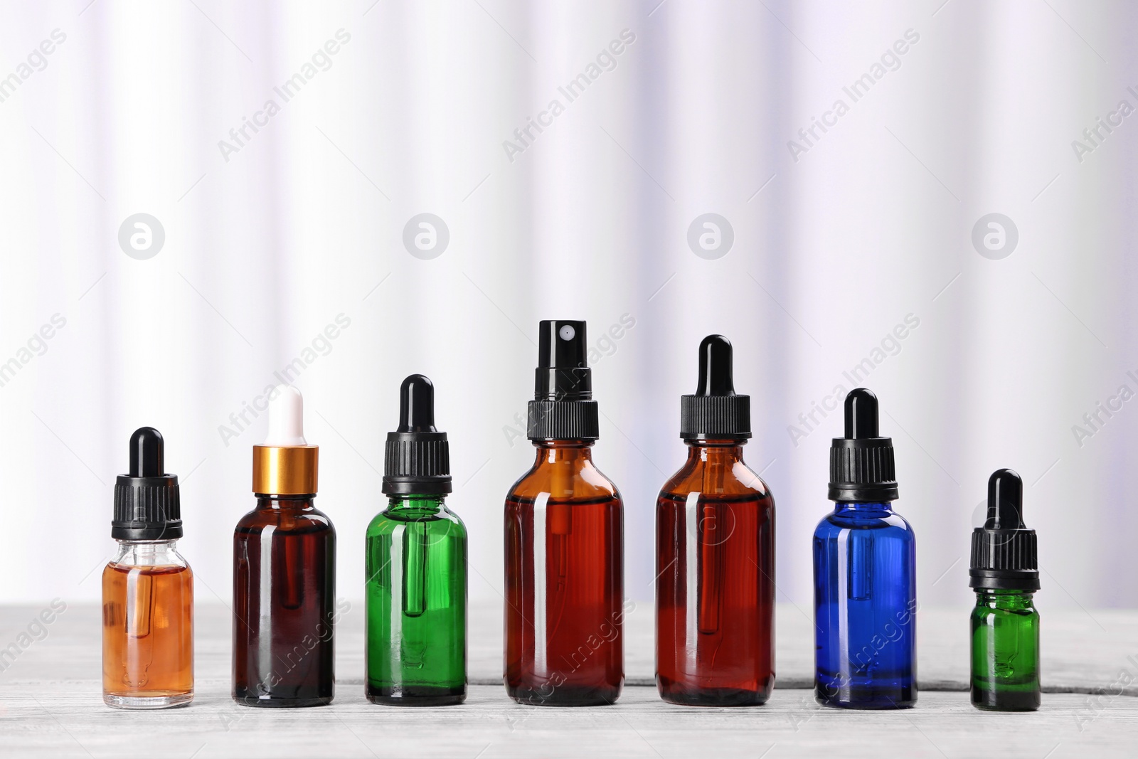 Photo of Bottles of essential oils on table against light background. Cosmetic products