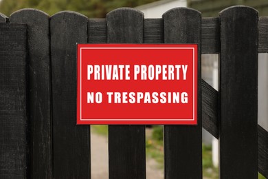 Red sign with text Private Property No Trespassing on wooden fence