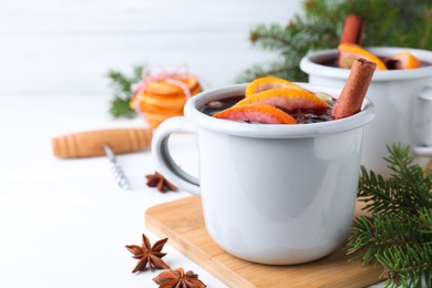 Photo of Aromatic mulled wine on white wooden table, closeup