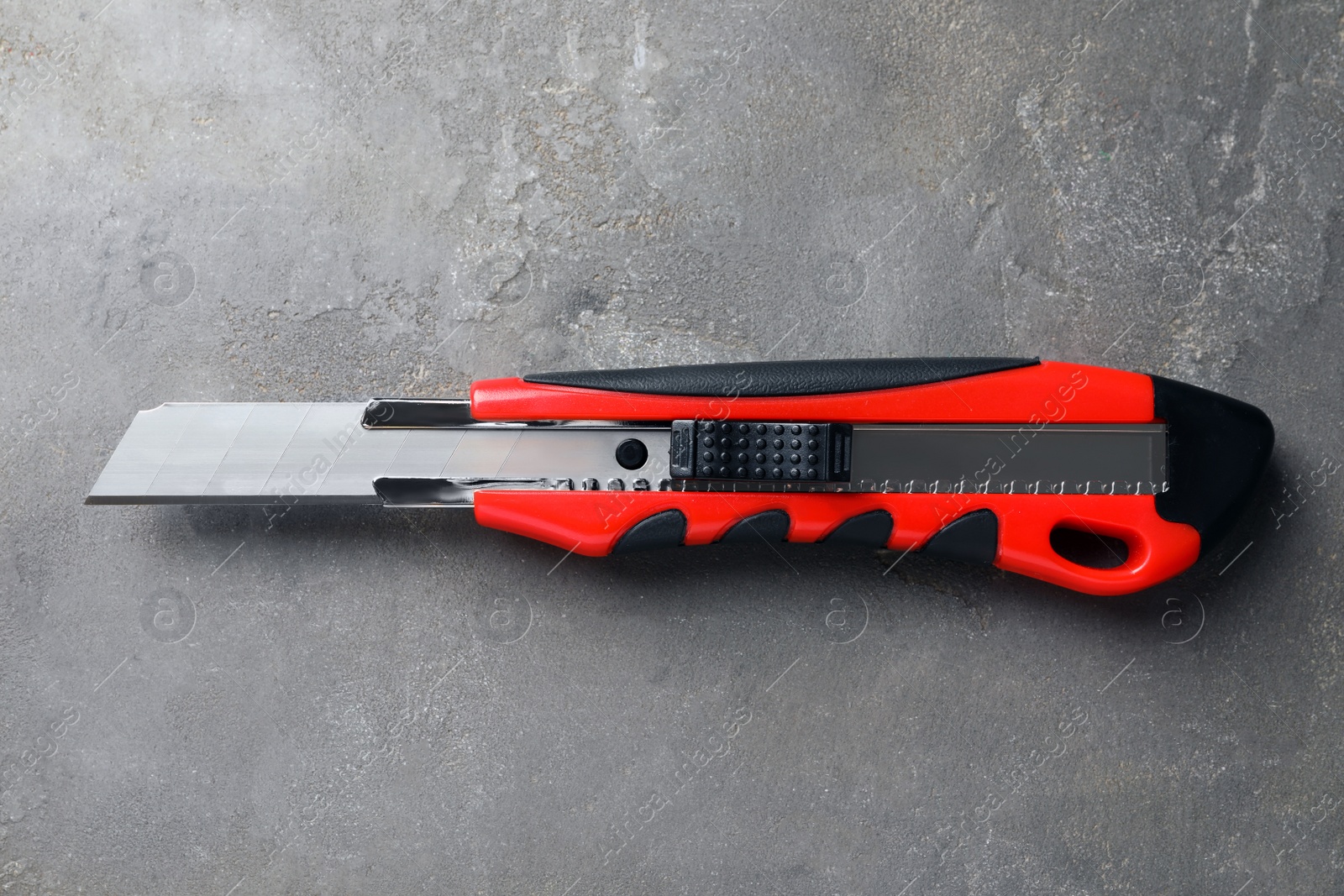 Photo of Utility knife on grey table, top view. Construction tool