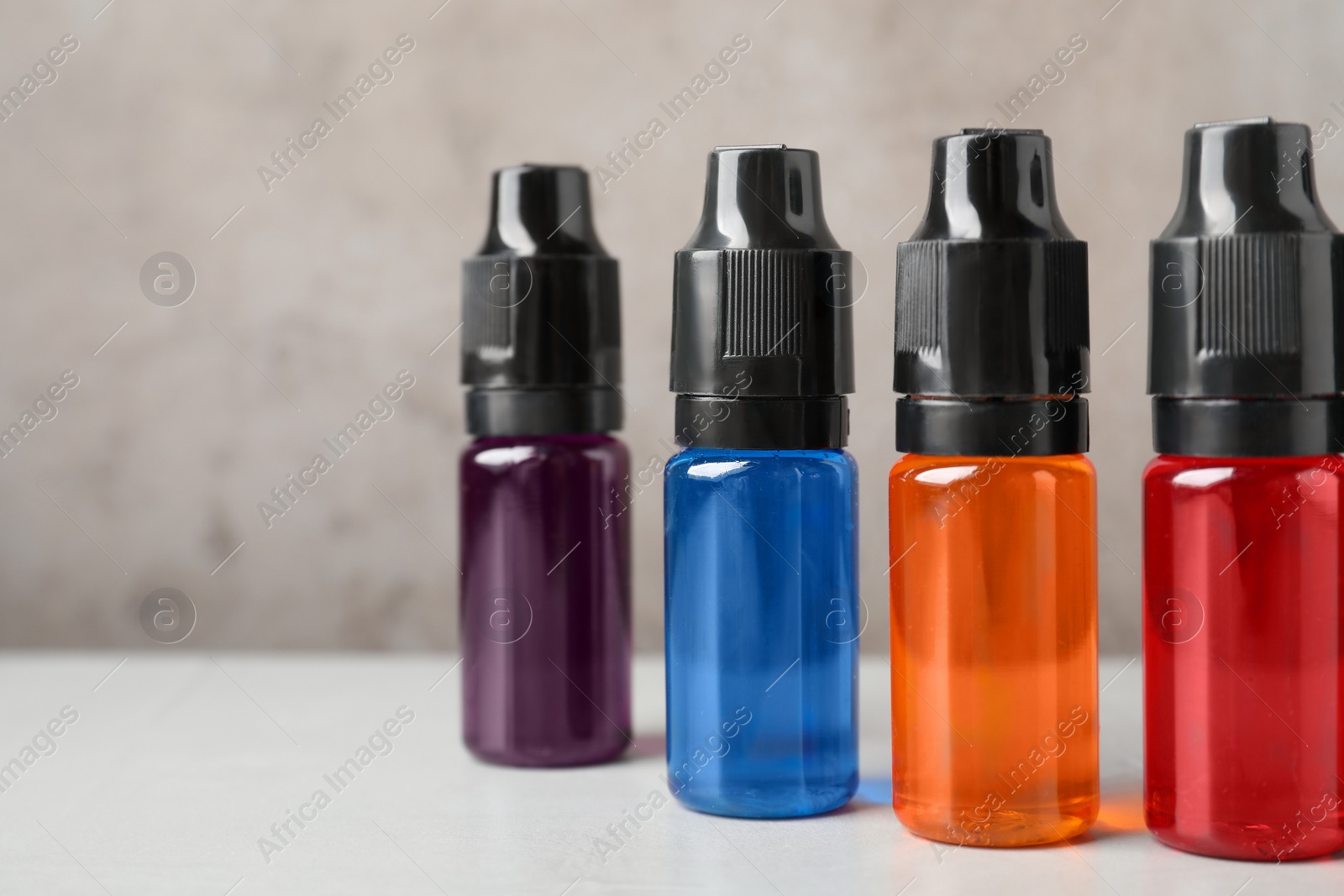 Photo of Bottles with different food coloring on white table, closeup