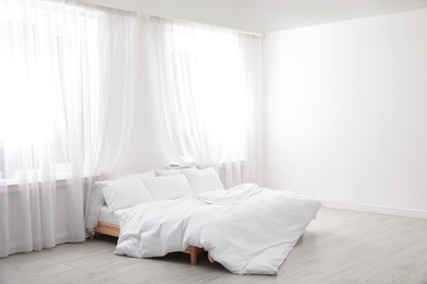 Photo of Comfortable bed in light room. Interior design