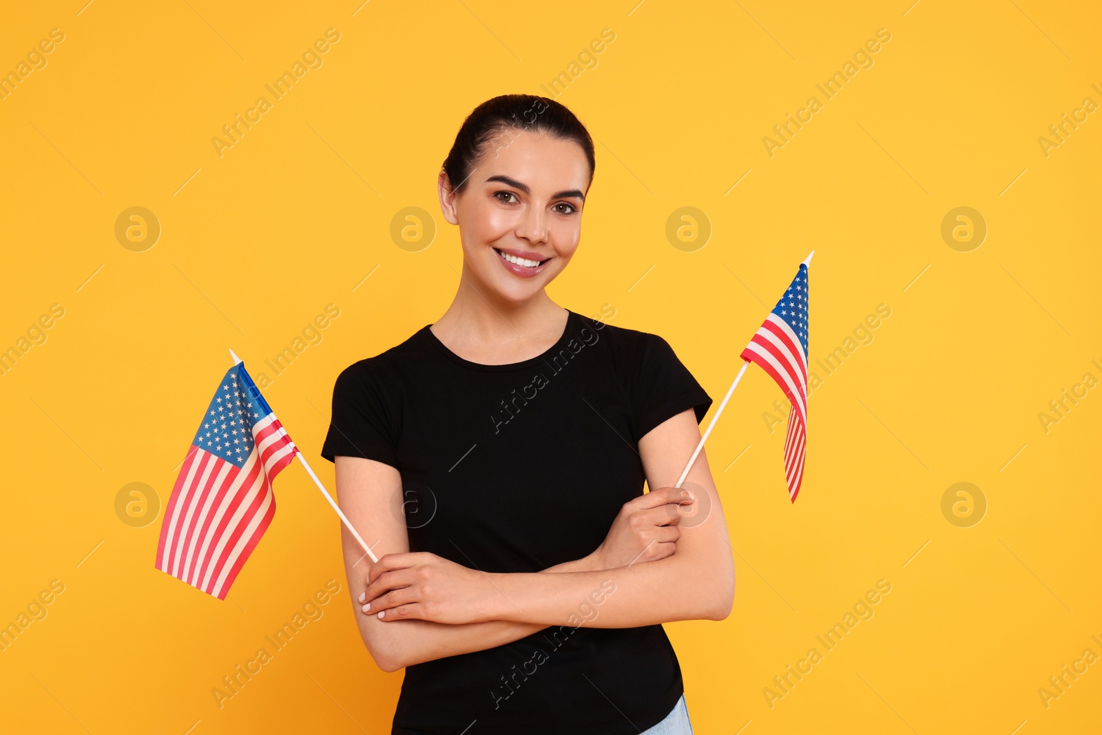 Photo of 4th of July - Independence Day of USA. Happy woman with American flags on yellow background