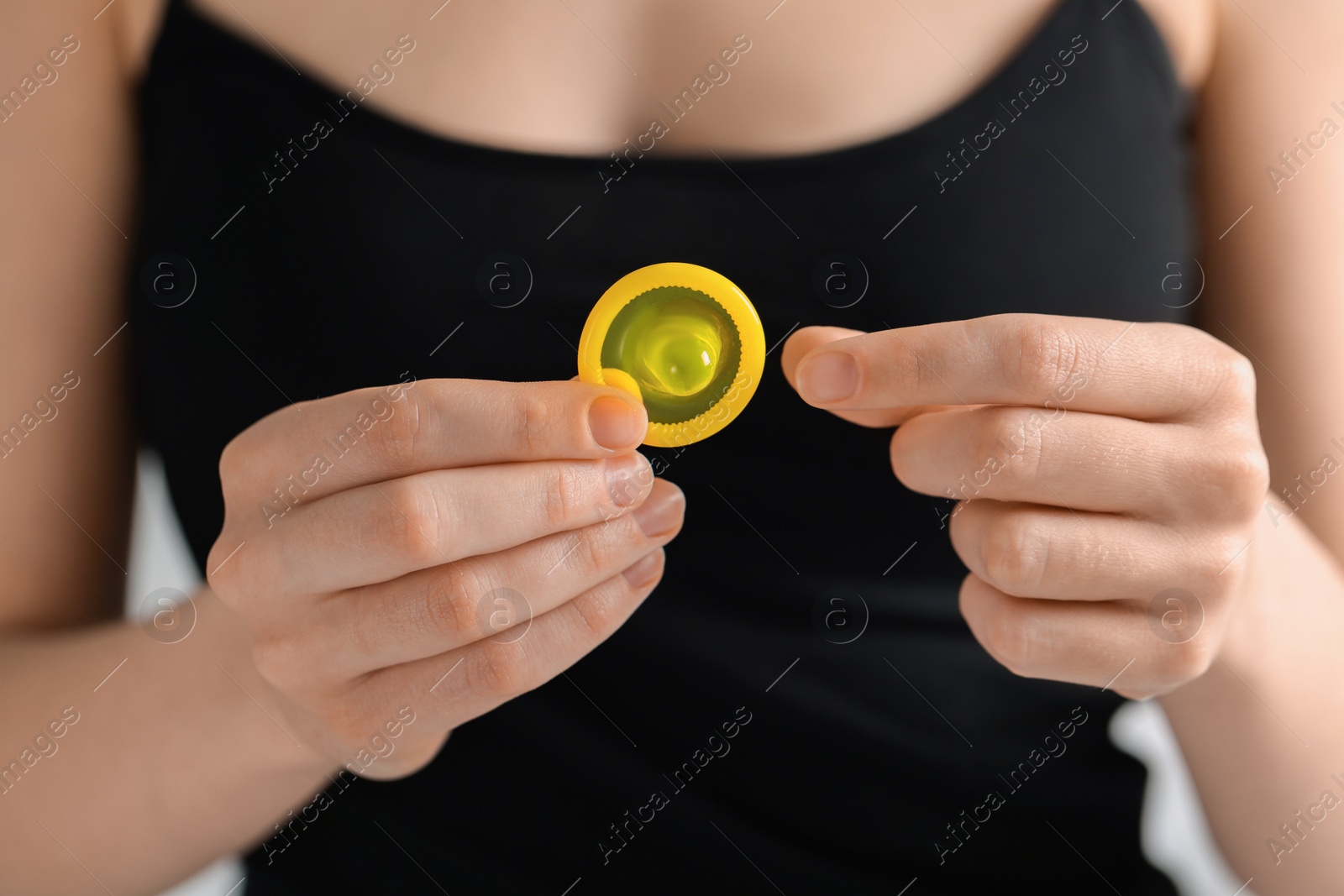 Photo of Woman holding unpacked condom, closeup. Safe sex