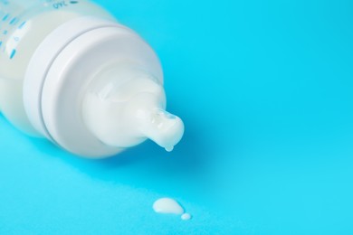 One feeding bottle with milk on light blue background, closeup. Space for text
