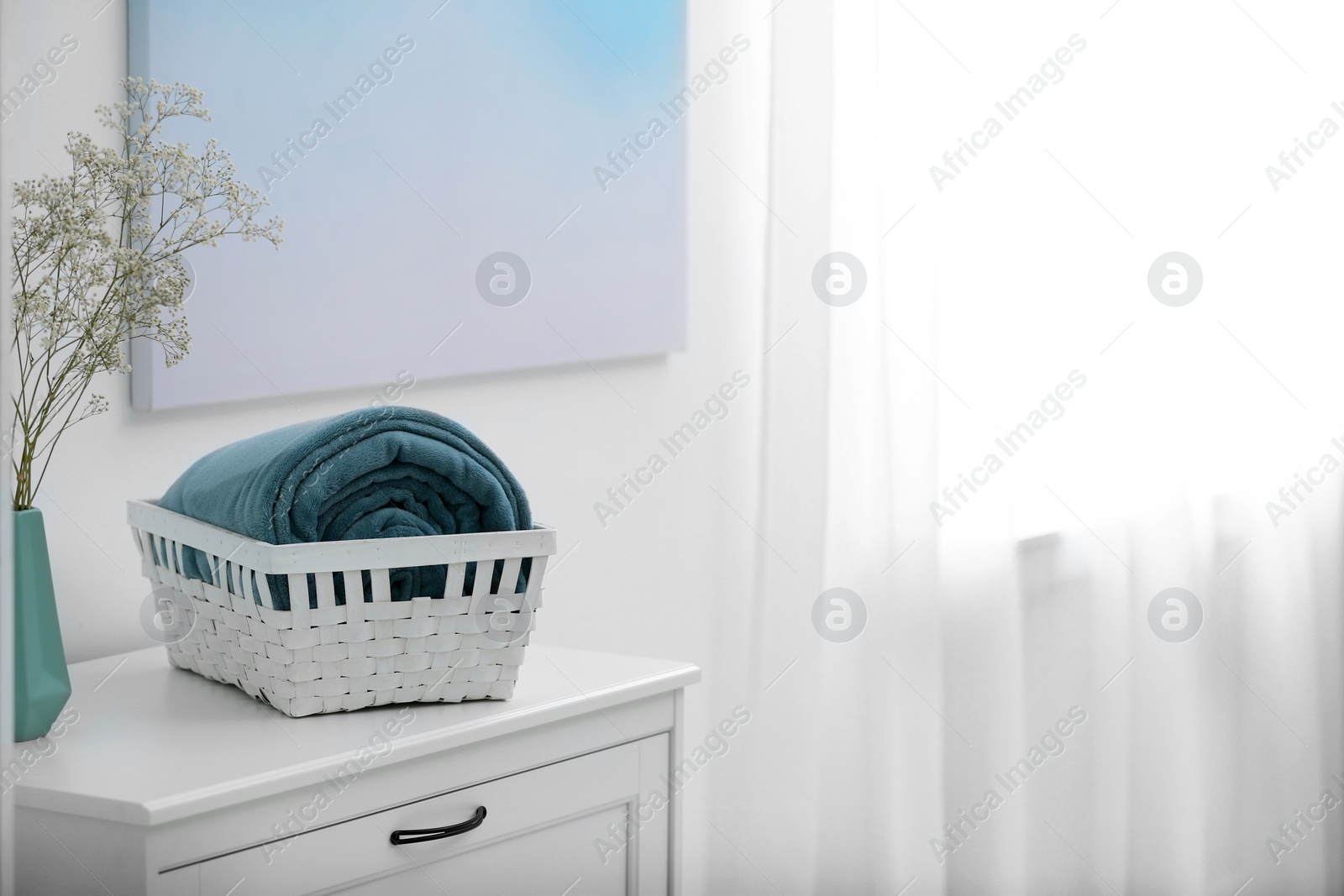 Photo of Basket with soft plaid on commode in room. Space for text